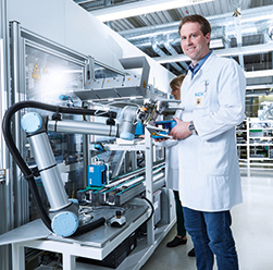 man standing next to robotic arm used in electronics industry