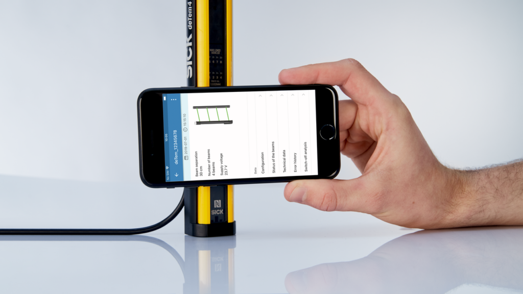 Hand holds smart phone near deTec4 safety light curtain to see overview of light curtain status with NFC